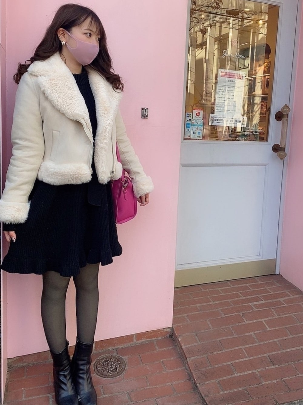 ブラック系のワンピース、ピンク系のショルダーバッグ、ブラック系のブーツを着用したレディースの冬コーディネートの1枚目の写真