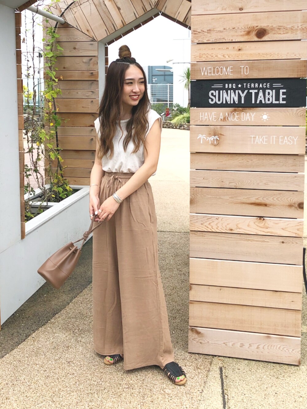 ベージュ系のTシャツ/カットソー、ブラウン系のその他パンツ、ブラック系のサンダルを着用したレディースの夏コーディネートの1枚目の写真