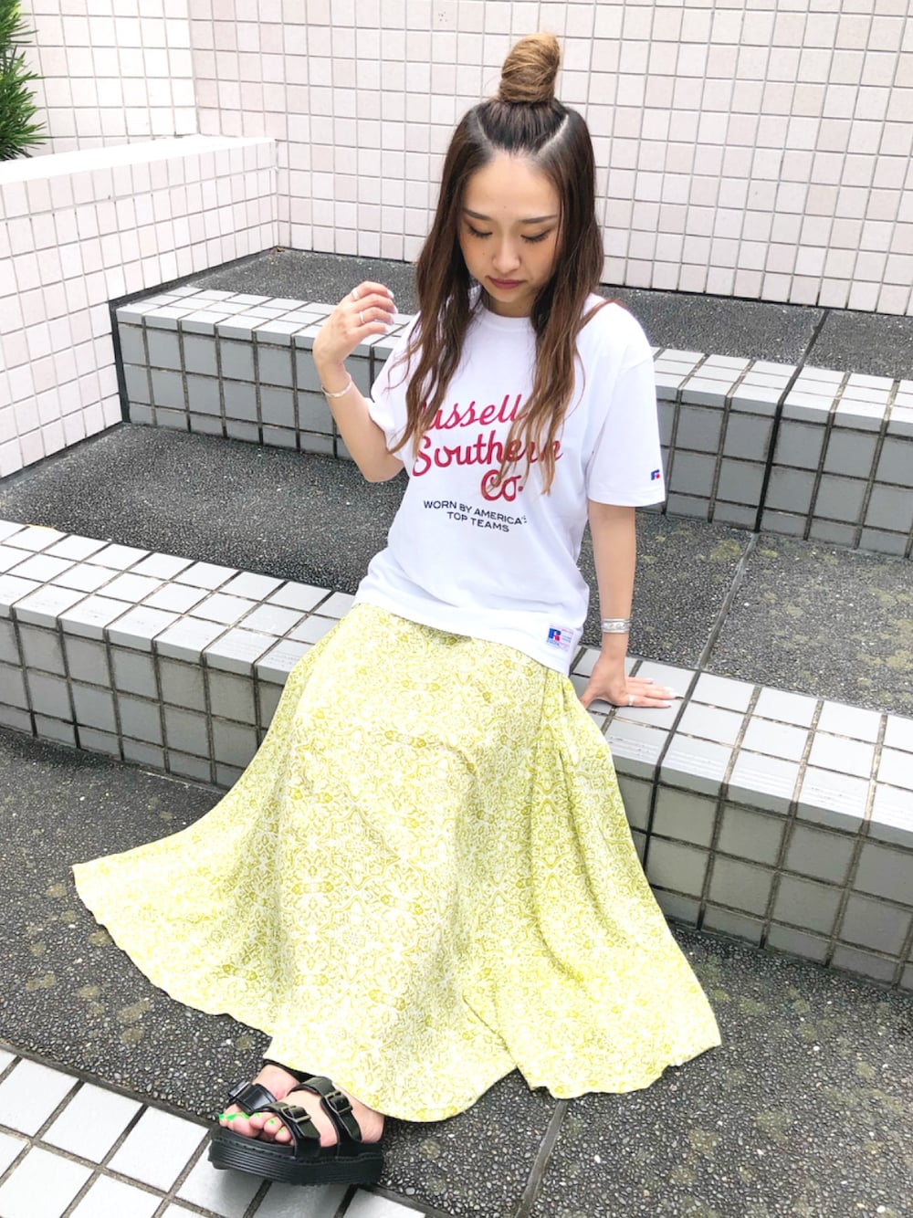 ホワイト系のTシャツ/カットソー、グリーン系のスカート、ブラック系のサンダルを着用したレディースの夏コーディネートの1枚目の写真