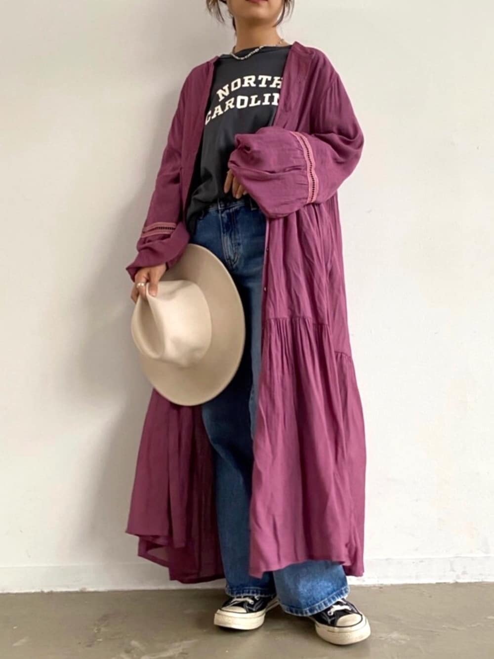 グレー系のTシャツ/カットソー、レッド系のワンピース、ブルー系のデニムパンツを着用したレディースの秋コーディネートの1枚目の写真