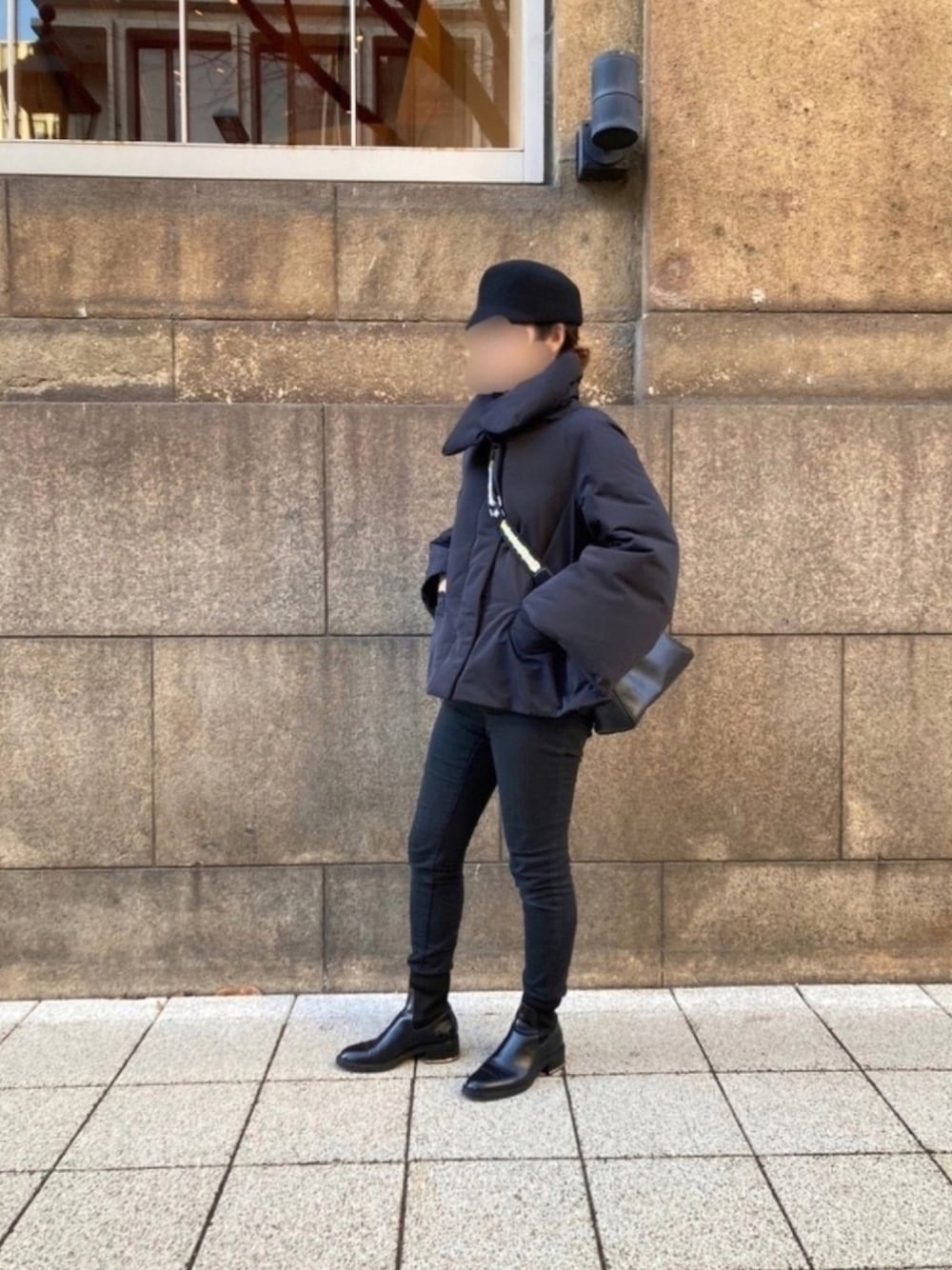 シルバー系のショルダーバッグ、ブラック系のダウンジャケット/コート、ブラック系のパンツを着用したレディースの冬コーディネートの1枚目の写真