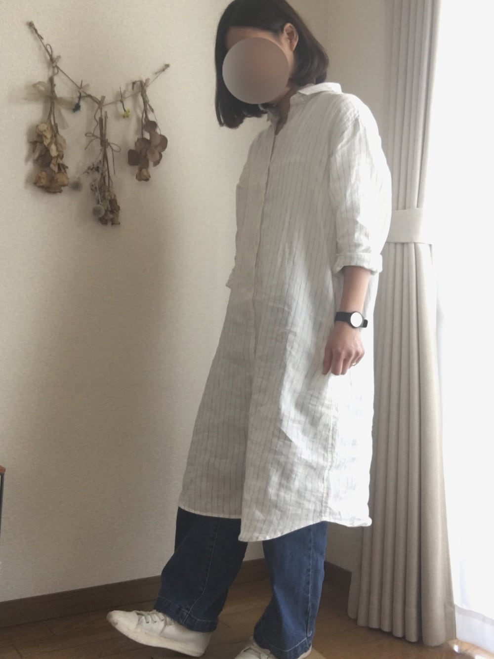 ホワイト系のシャツワンピース、ブルー系のデニムパンツを着用したレディースの春コーディネートの1枚目の写真