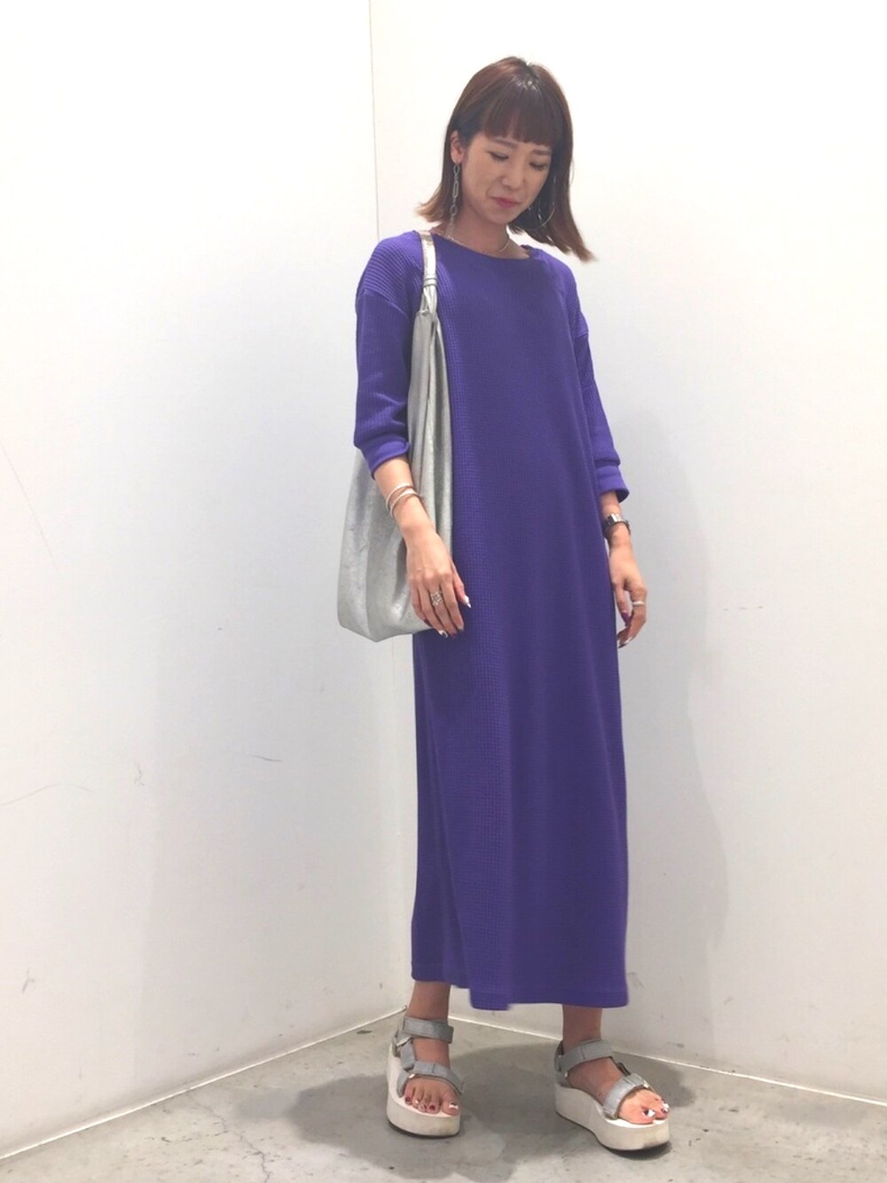 パープル系のワンピース、シルバー系のサンダル、シルバー系のバッグを着用したレディースの夏コーディネートの1枚目の写真