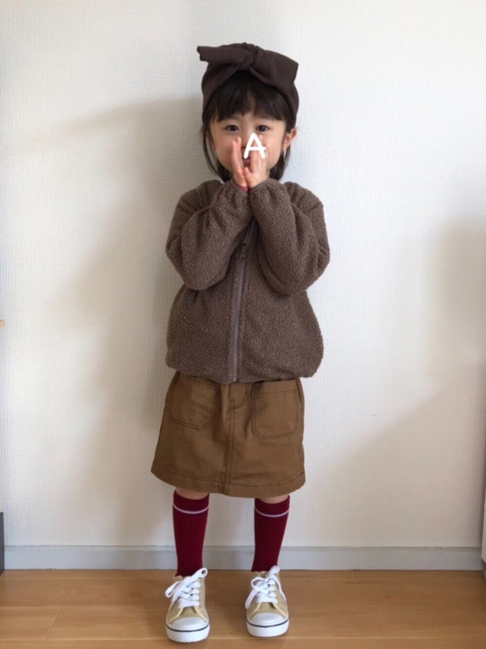 ブラウン系のブルゾン、ベージュ系のスカート、ベージュ系のスニーカーを着用したキッズの秋コーディネートの1枚目の写真