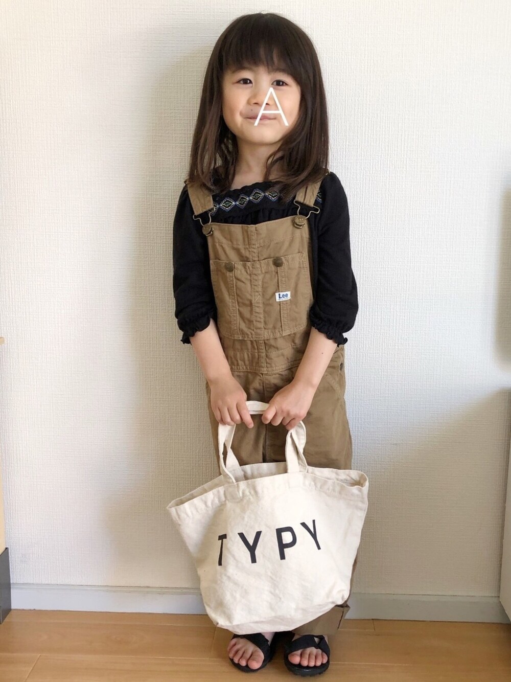 ブラック系のTシャツ/カットソー、ベージュ系のその他パンツ、ブラック系のサンダルを着用したキッズの春コーディネートの1枚目の写真