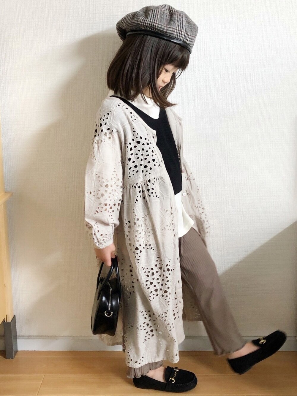 グレー系のワンピース、ブラック系のベスト、ベージュ系のTシャツ/カットソーを着用したキッズの秋コーディネートの1枚目の写真