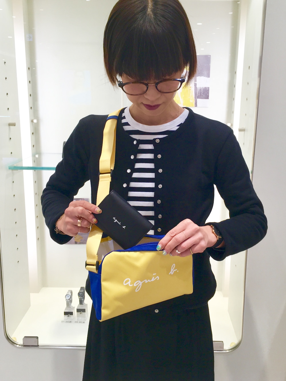 イエロー系のショルダーバッグ、ブラック系のカーディガン/ボレロ、ブラック系のTシャツ/カットソーを着用したレディースの冬コーディネートの1枚目の写真