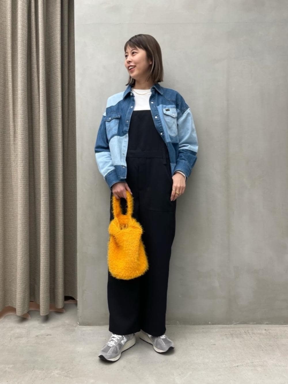 グレー系のスニーカー、ホワイト系のTシャツ/カットソー、オレンジ系のトートバッグを着用したレディースの冬コーディネートの1枚目の写真