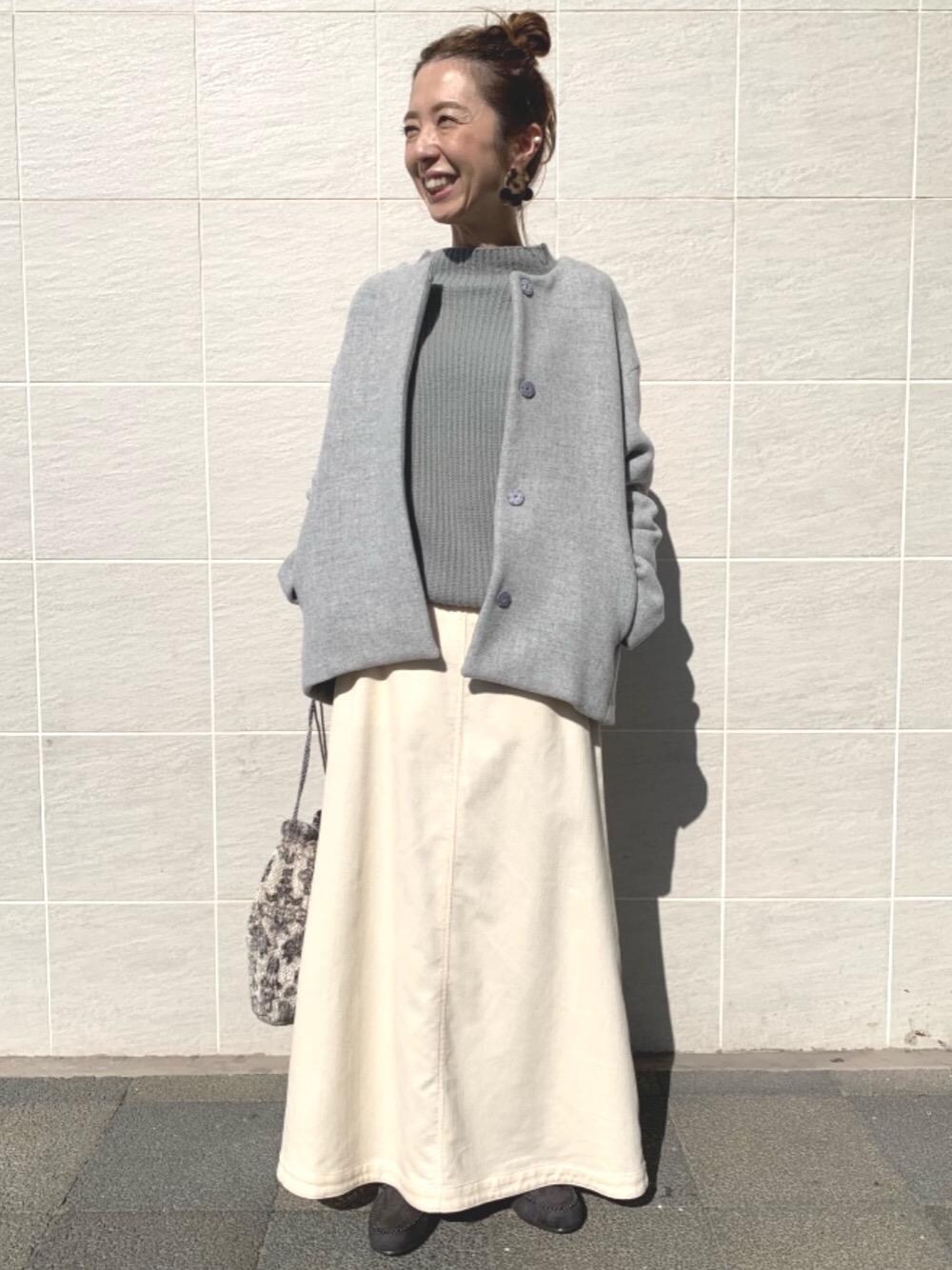 グリーン系のニット/セーター、グレー系のノーカラーコート、グレー系のモカシン/デッキシューズを着用したレディースの秋コーディネートの1枚目の写真