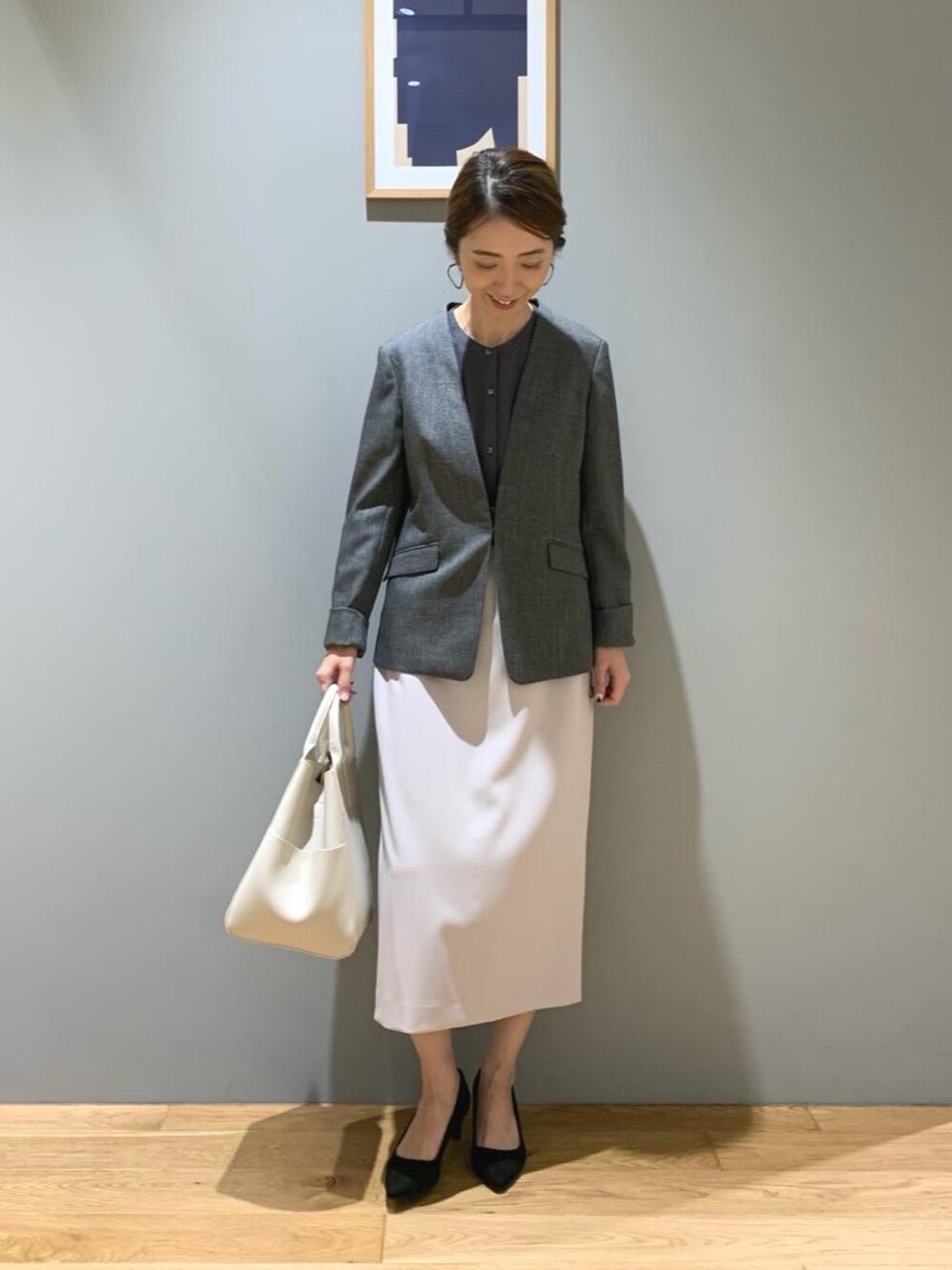 ブラック系のパンプス、ホワイト系のショルダーバッグ、グレー系のノーカラージャケットを着用したレディースの秋コーディネートの1枚目の写真