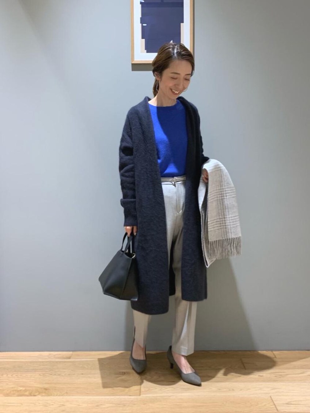 グレー系のパンプス、グレー系のカーディガン/ボレロ、ブルー系のニット/セーターを着用したレディースの冬コーディネートの1枚目の写真