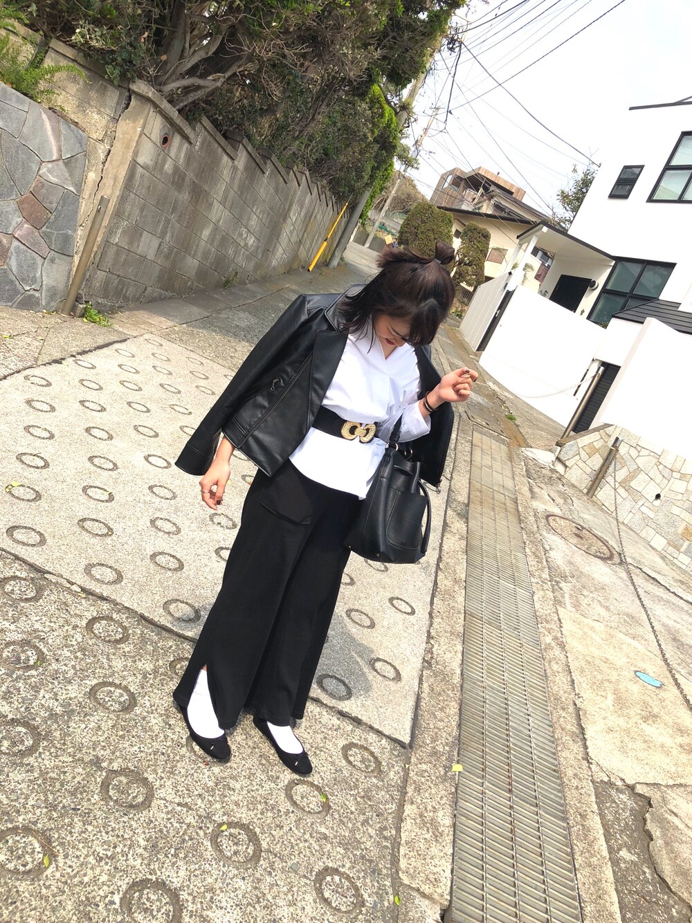 ブラック系のハンドバッグ、ブラック系のライダースジャケット、ホワイト系のシャツ/ブラウスを着用したレディースの春コーディネートの1枚目の写真