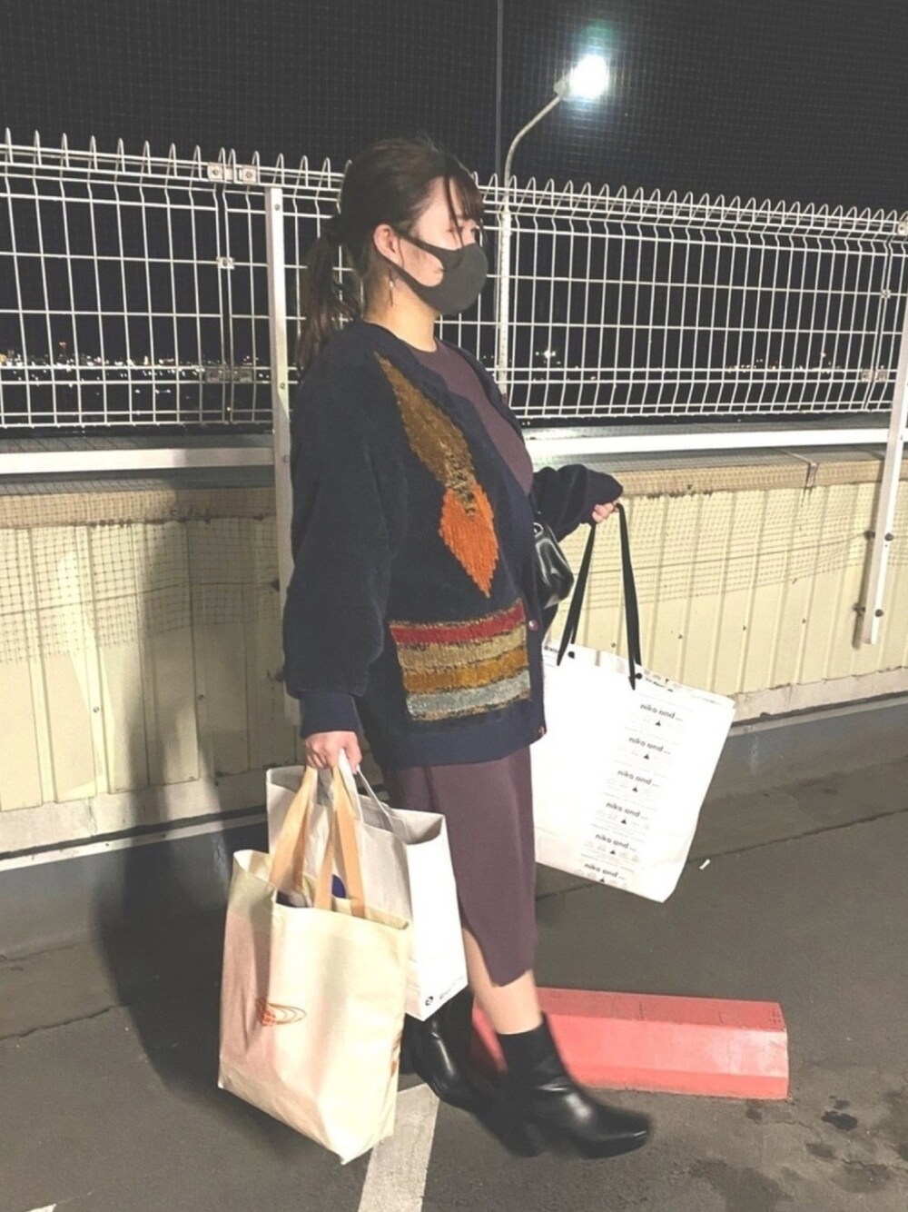 パープル系のワンピース、ブラック系のブーツ、ブラック系のバッグを着用したレディースの冬コーディネートの1枚目の写真