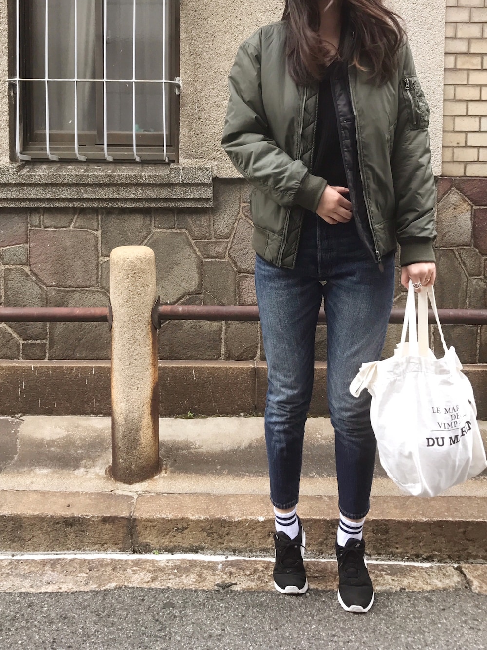 ブラック系のスニーカー、ブルー系のデニムパンツ、ブラック系のジャケット/アウターを着用したレディースの冬コーディネートの1枚目の写真
