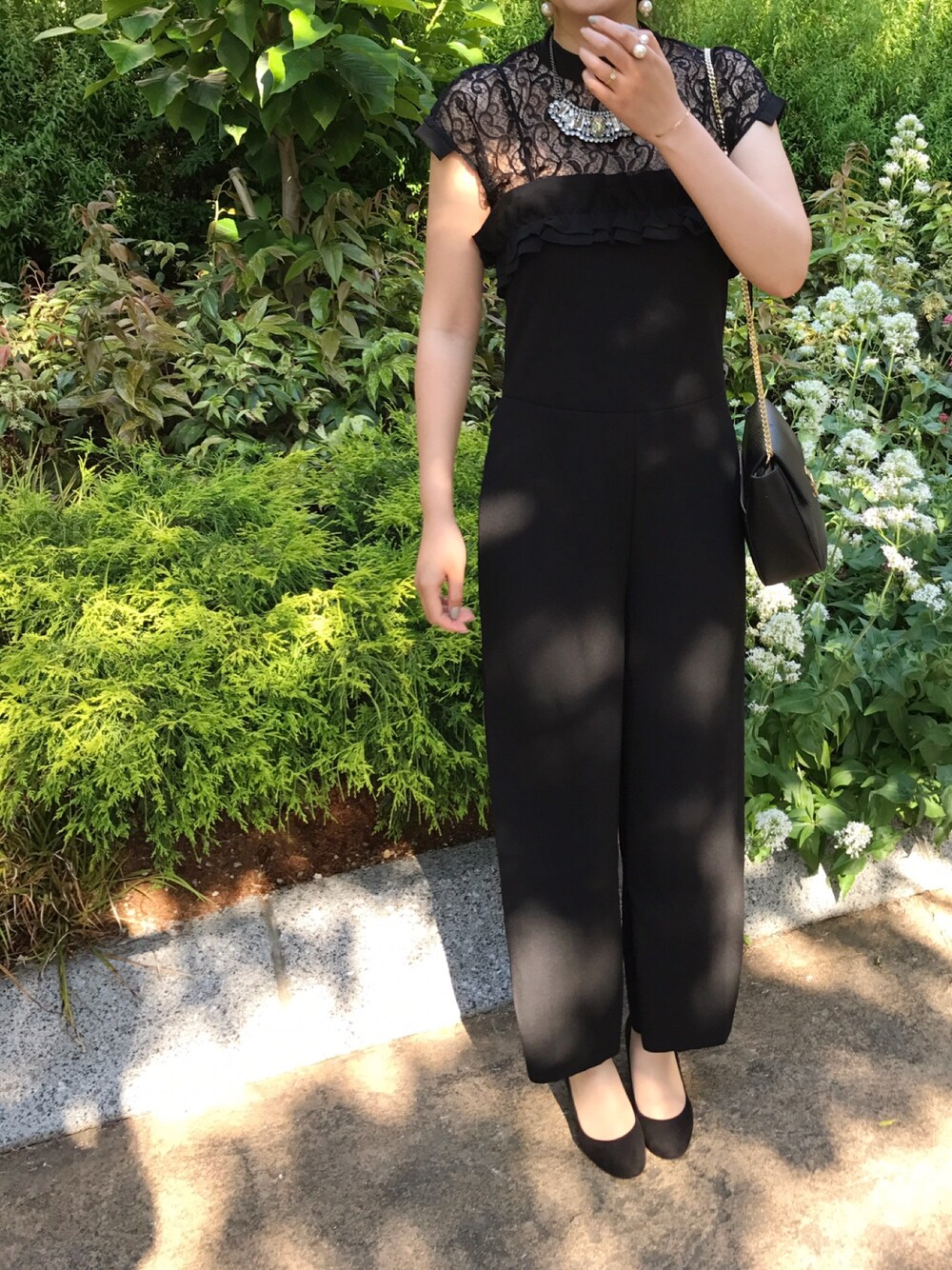 ブラック系のつなぎ/オールインワン、ブラック系のショルダーバッグ、ホワイト系のピアス（両耳用）を着用したレディースの夏コーディネートの1枚目の写真