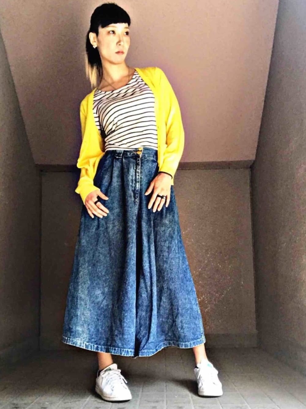 イエロー系のカーディガン/ボレロ、ブルー系のデニムパンツ、ホワイト系のスニーカーを着用したレディースの春コーディネートの1枚目の写真