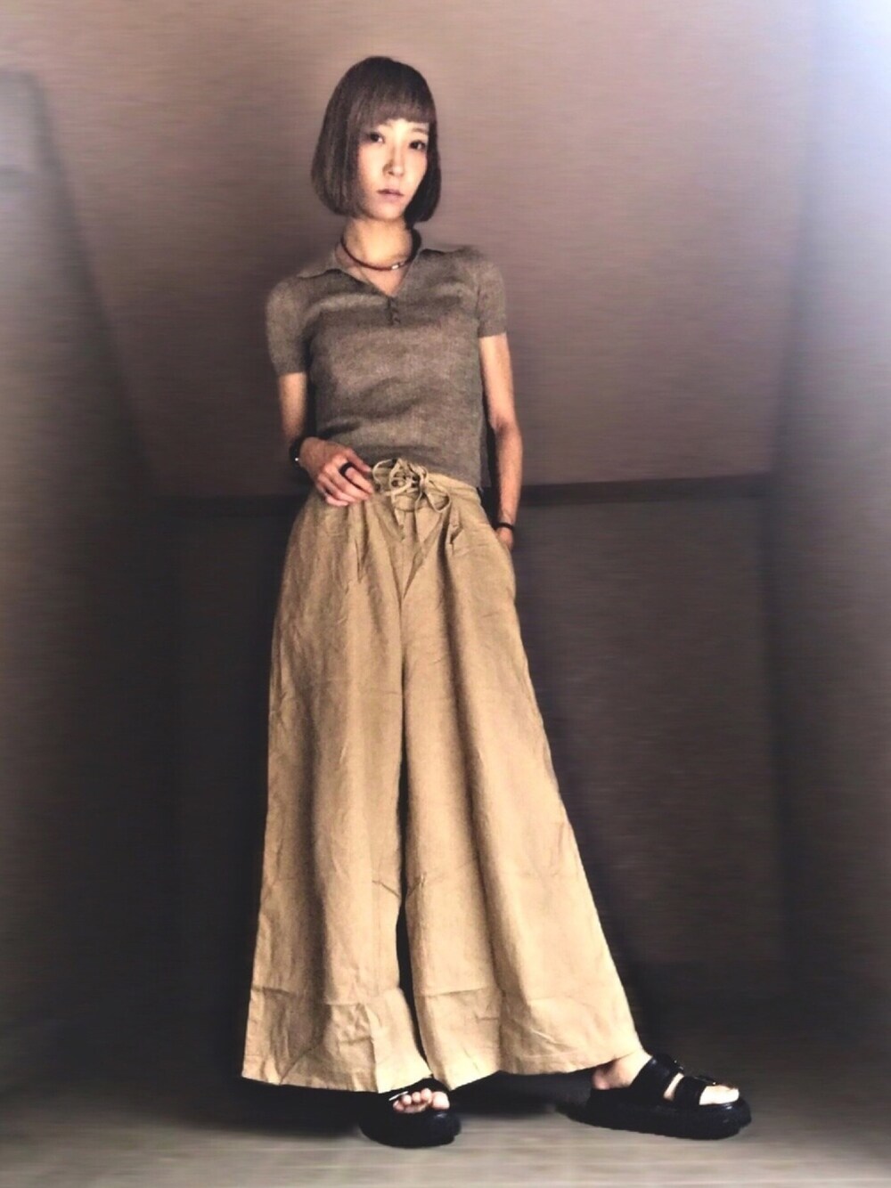 ブラウン系のニット/セーター、ベージュ系のその他パンツ、ブラック系のサンダルを着用したレディースの秋コーディネートの1枚目の写真