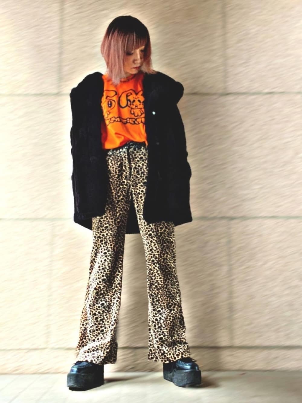 オレンジ系のTシャツ/カットソー、ブラック系のジャケット/アウター、ブラウン系のパンツを着用したレディースの冬コーディネートの1枚目の写真