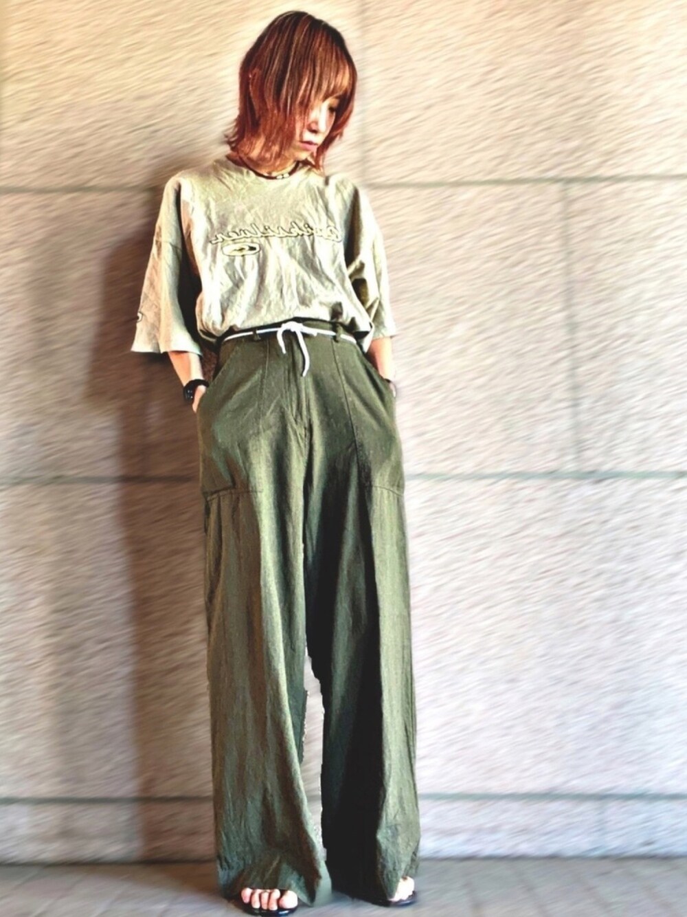 ベージュ系のTシャツ/カットソー、グリーン系のパンツ、ブラック系のサンダルを着用したレディースの夏コーディネートの1枚目の写真