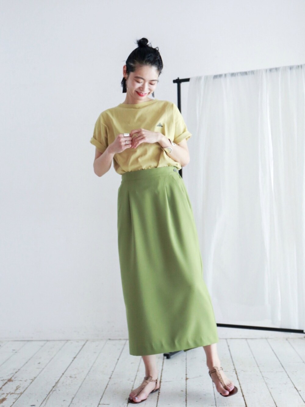 イエロー系のTシャツ/カットソー、グリーン系のスカートを着用したレディースの春コーディネートの1枚目の写真