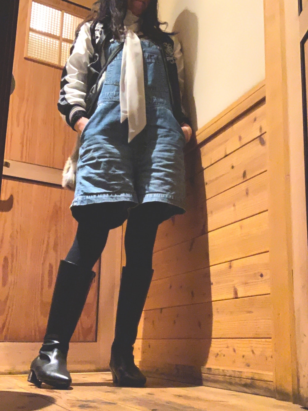 ブルー系のサロペット/オーバーオール、ブラック系のブーツ、ブラック系のスカジャンを着用したレディースの冬コーディネートの1枚目の写真