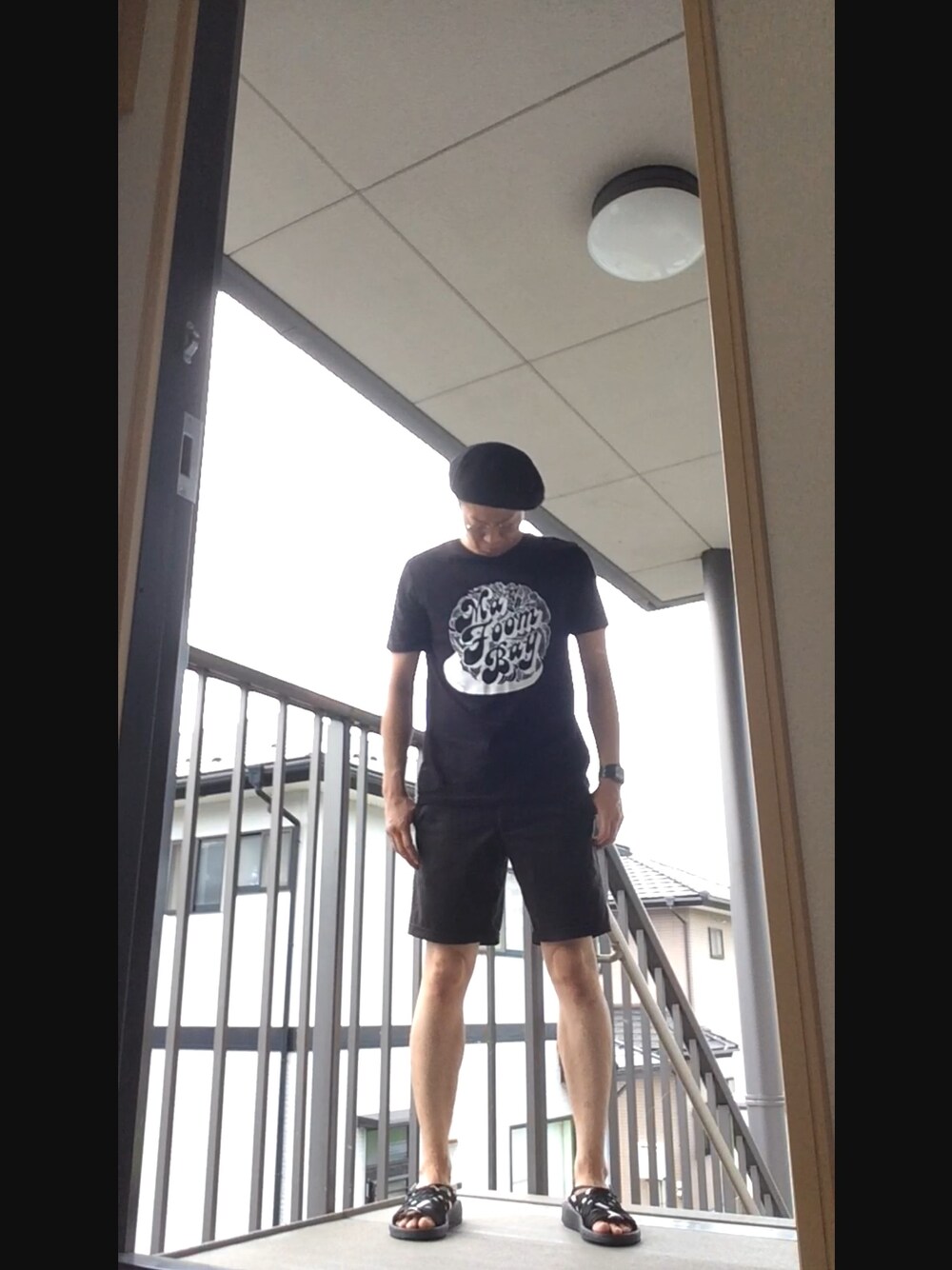 ブラック系のTシャツ/カットソー、ブラック系のチノパンツ、ホワイト系のサンダルを着用したメンズの夏コーディネートの1枚目の写真