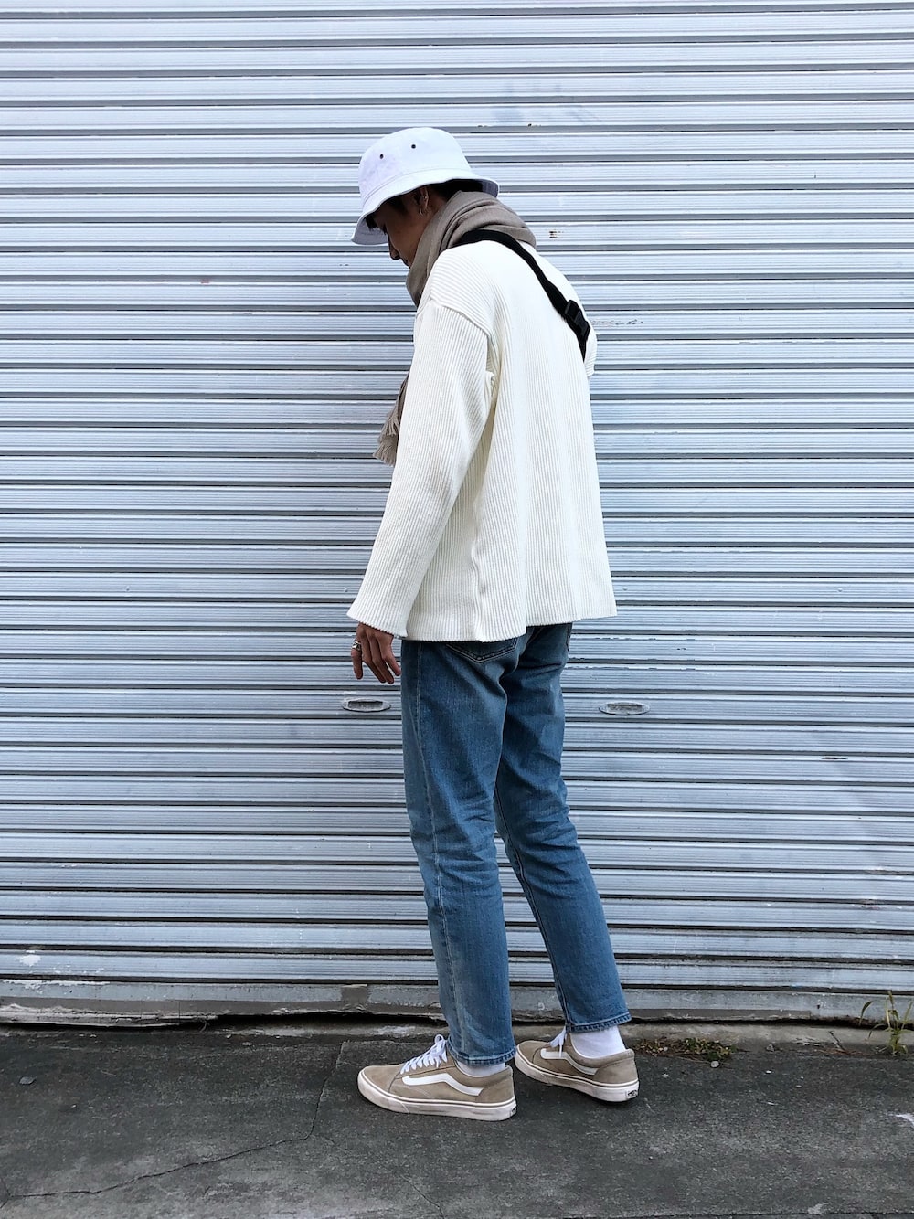 ホワイト系のニット/セーター、ブルー系のデニムパンツ、ベージュ系のスニーカーを着用したメンズの冬コーディネートの1枚目の写真