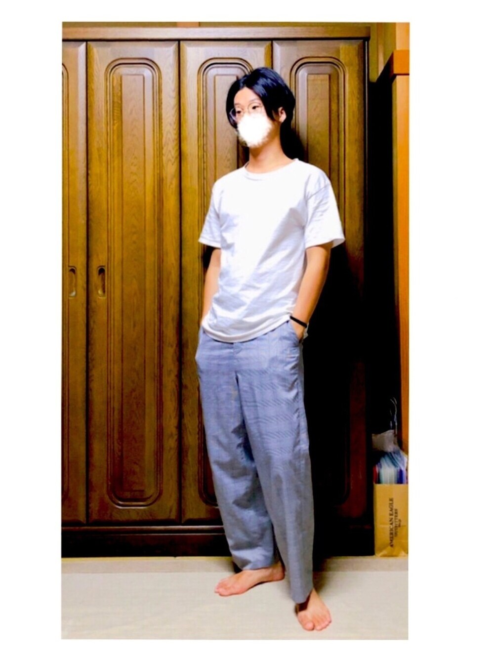 ホワイト系のTシャツ/カットソー、グレー系のスラックス、ブラック系のメガネを着用したメンズの夏コーディネートの1枚目の写真