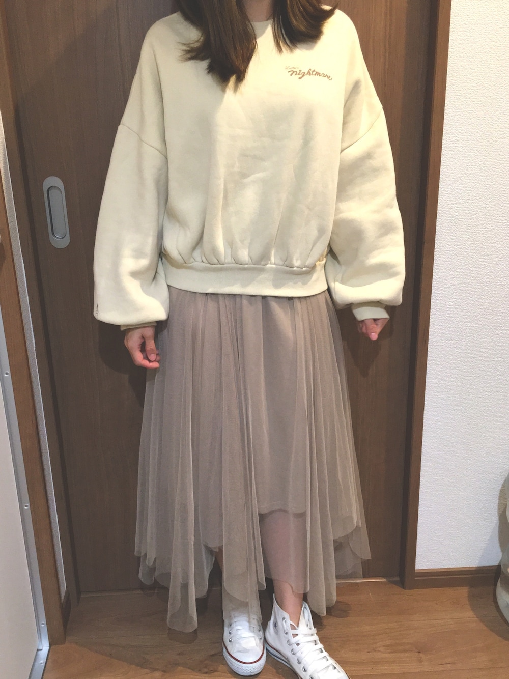 ベージュ系のスカート、ベージュ系のトップス、ホワイト系のスニーカーを着用したレディースの冬コーディネートの1枚目の写真