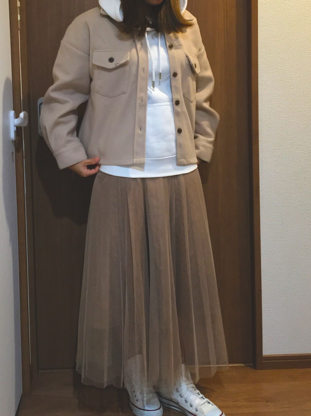 ベージュ系のカバーオール、ホワイト系のパーカー、ベージュ系のスカートを着用したレディースの冬コーディネートの1枚目の写真