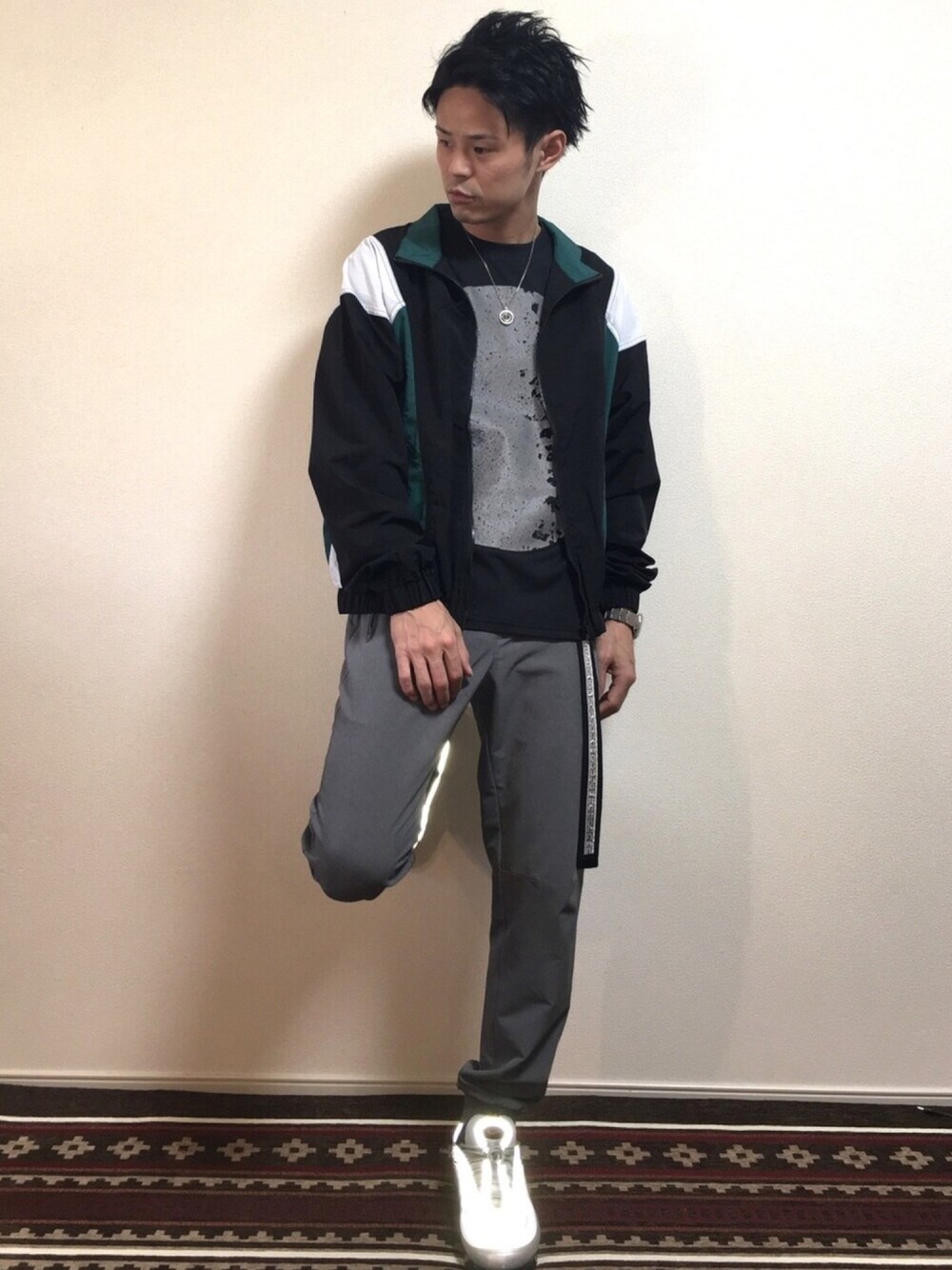 シルバー系のスニーカー、グリーン系のナイロンジャケット、ブラック系のTシャツ/カットソーを着用したメンズの春コーディネートの1枚目の写真
