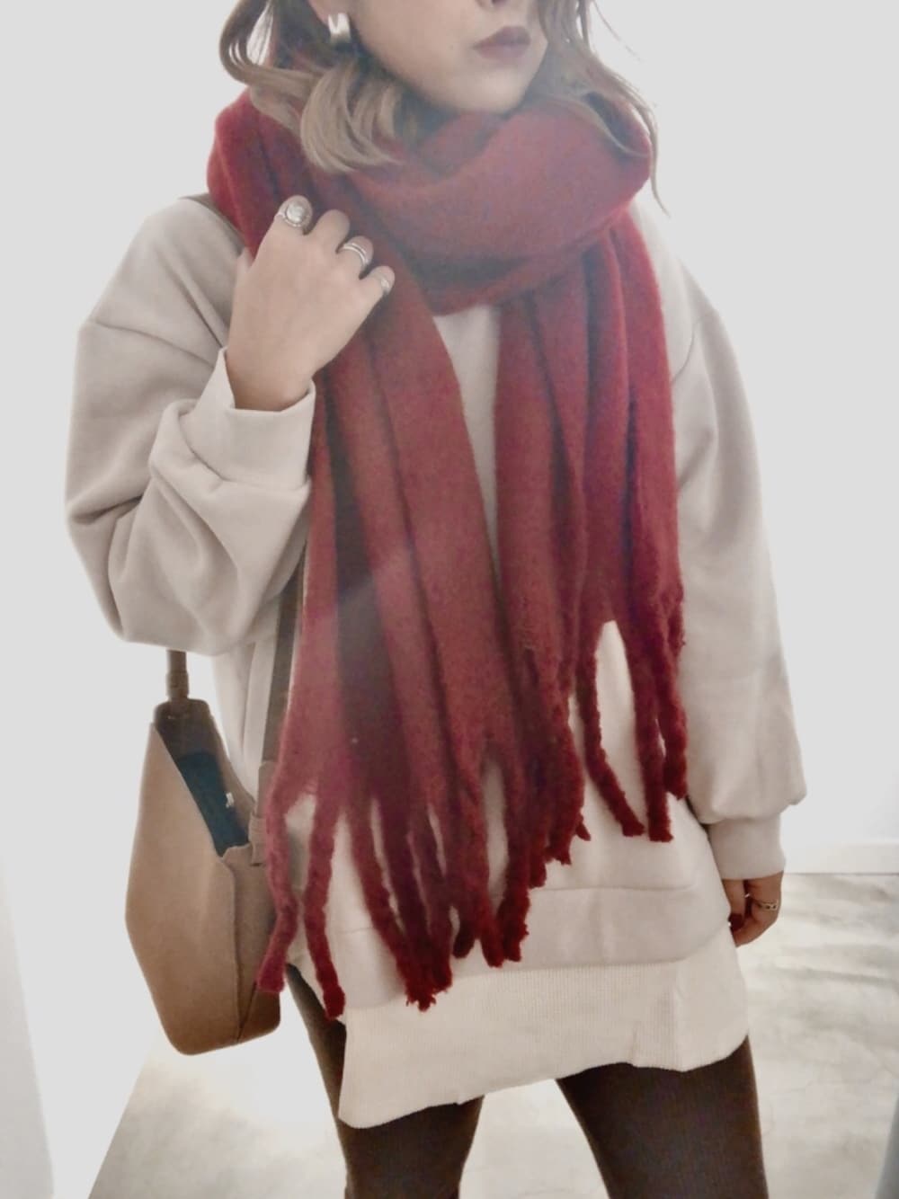 ベージュ系のスウェット、ブラウン系のショルダーバッグ、レッド系のマフラーを着用したレディースの秋コーディネートの1枚目の写真