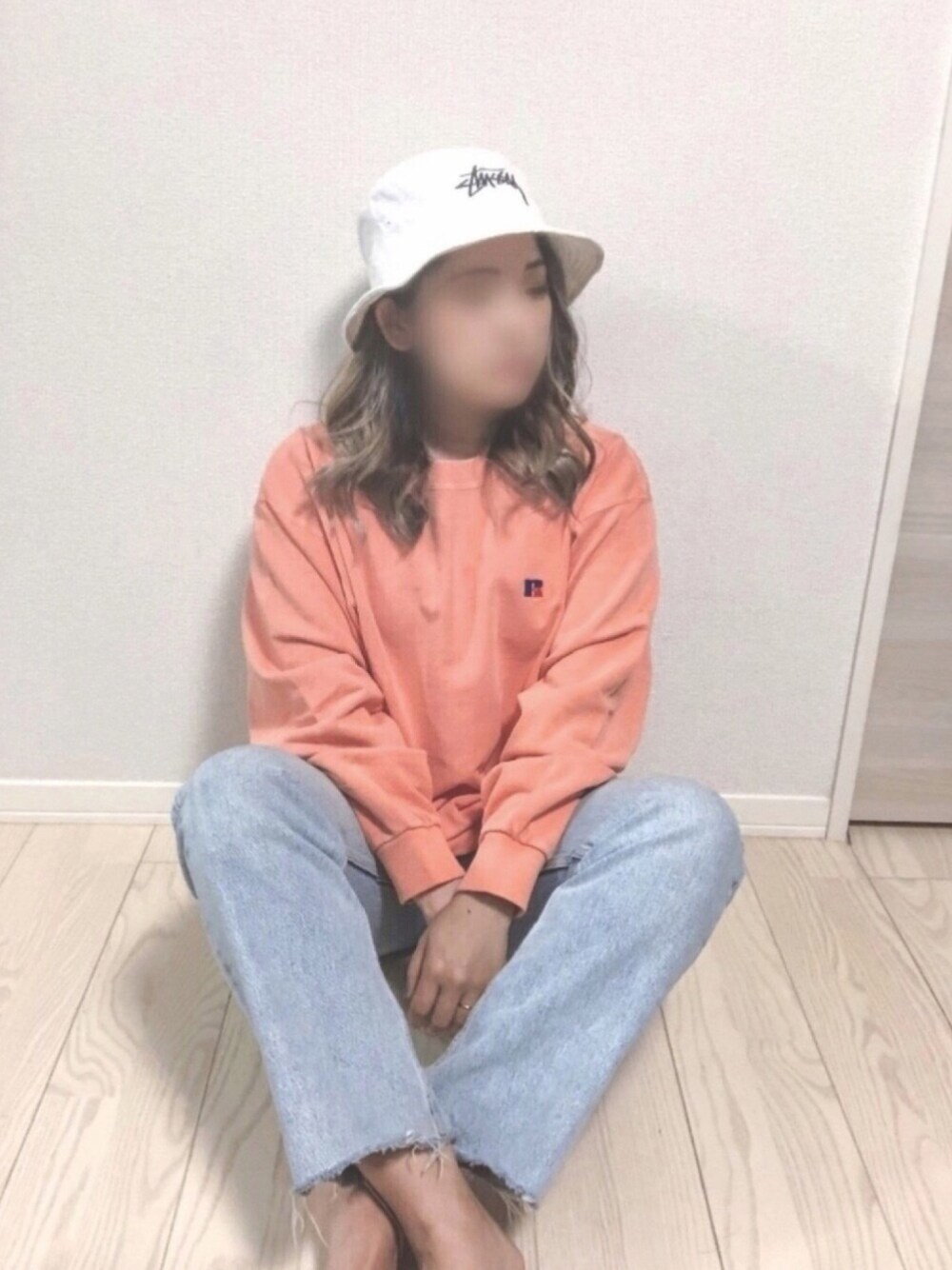 オレンジ系のスウェットを着用したレディースの春コーディネートの1枚目の写真