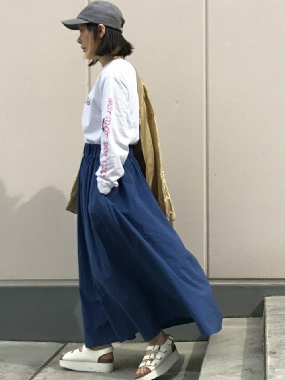 ホワイト系のTシャツ/カットソー、ブルー系のスカート、ホワイト系のサンダルを着用したレディースの春コーディネートの1枚目の写真