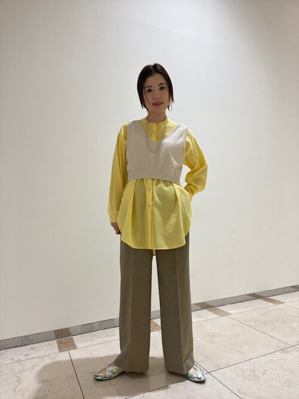 ベージュ系のニット/セーター、グリーン系のその他パンツ、イエロー系のシャツ/ブラウスを着用したレディースの春コーディネートの1枚目の写真