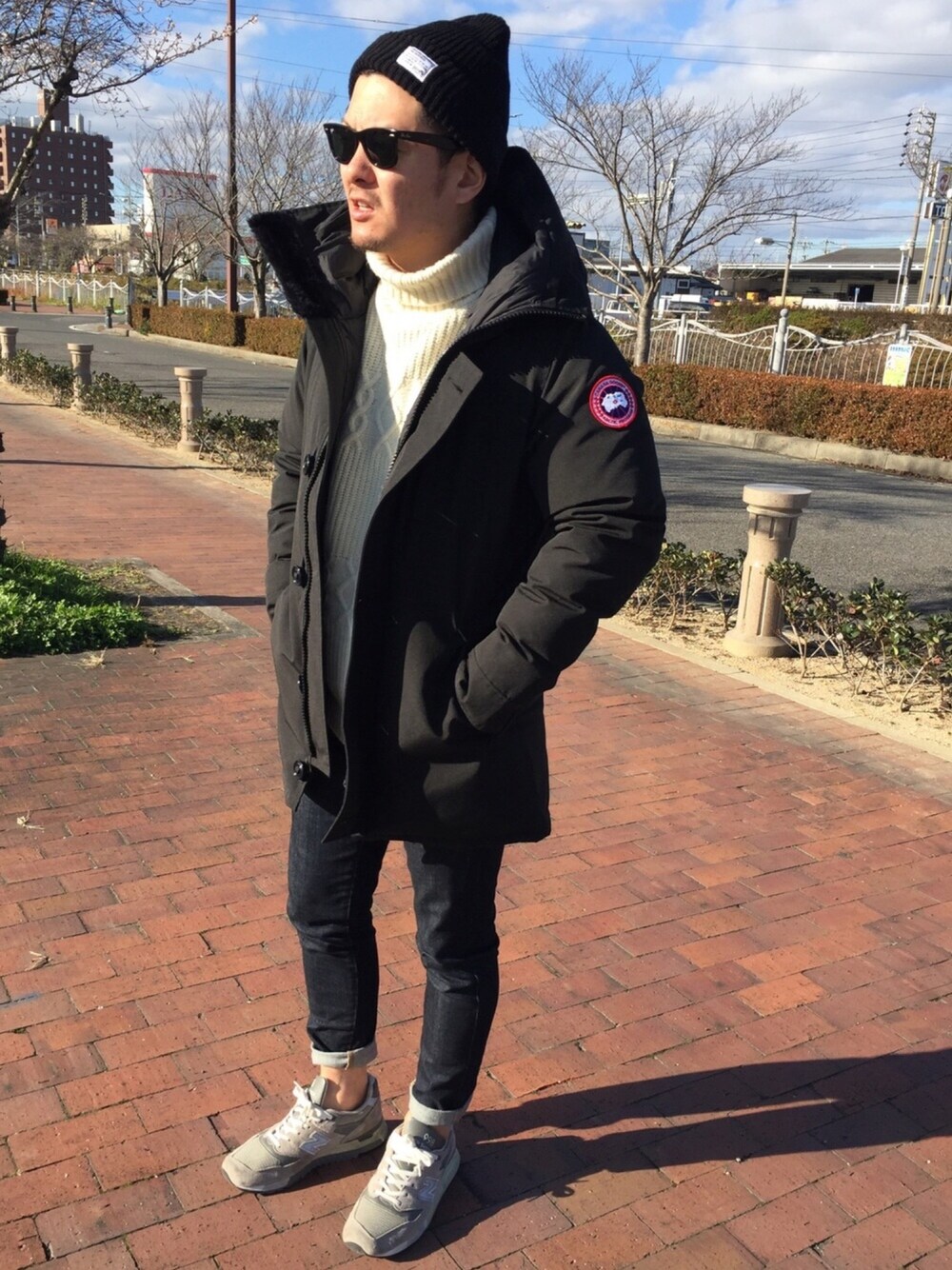 ブラック系のダウンジャケット/コート、ホワイト系のニット/セーター、ブルー系のデニムパンツを着用したメンズの冬コーディネートの1枚目の写真