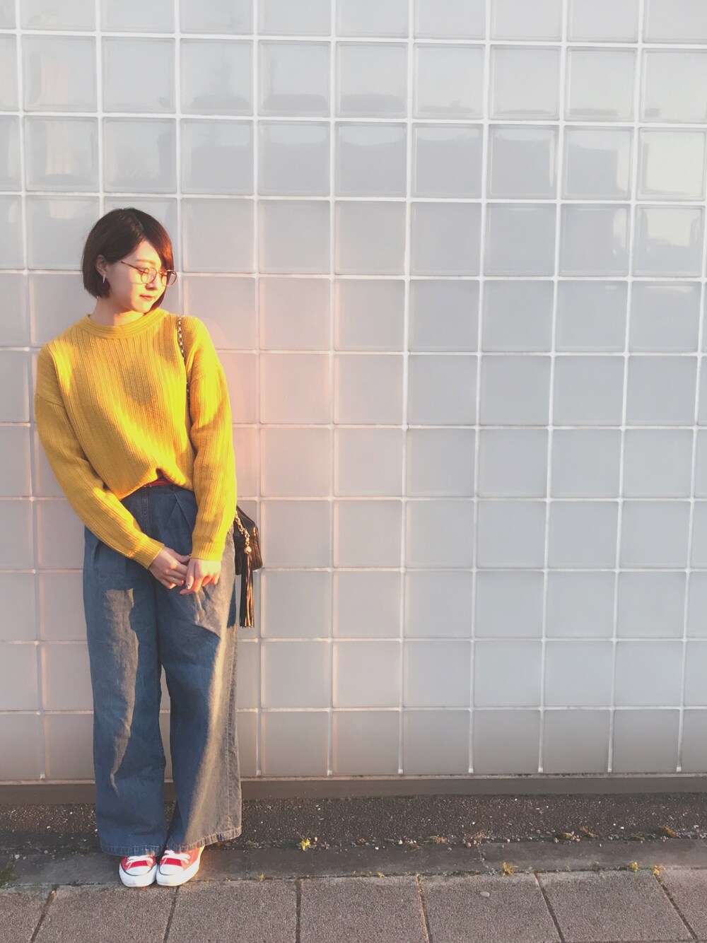 イエロー系のニット/セーター、ブルー系のデニムパンツ、ブラック系のショルダーバッグを着用したレディースの冬コーディネートの1枚目の写真