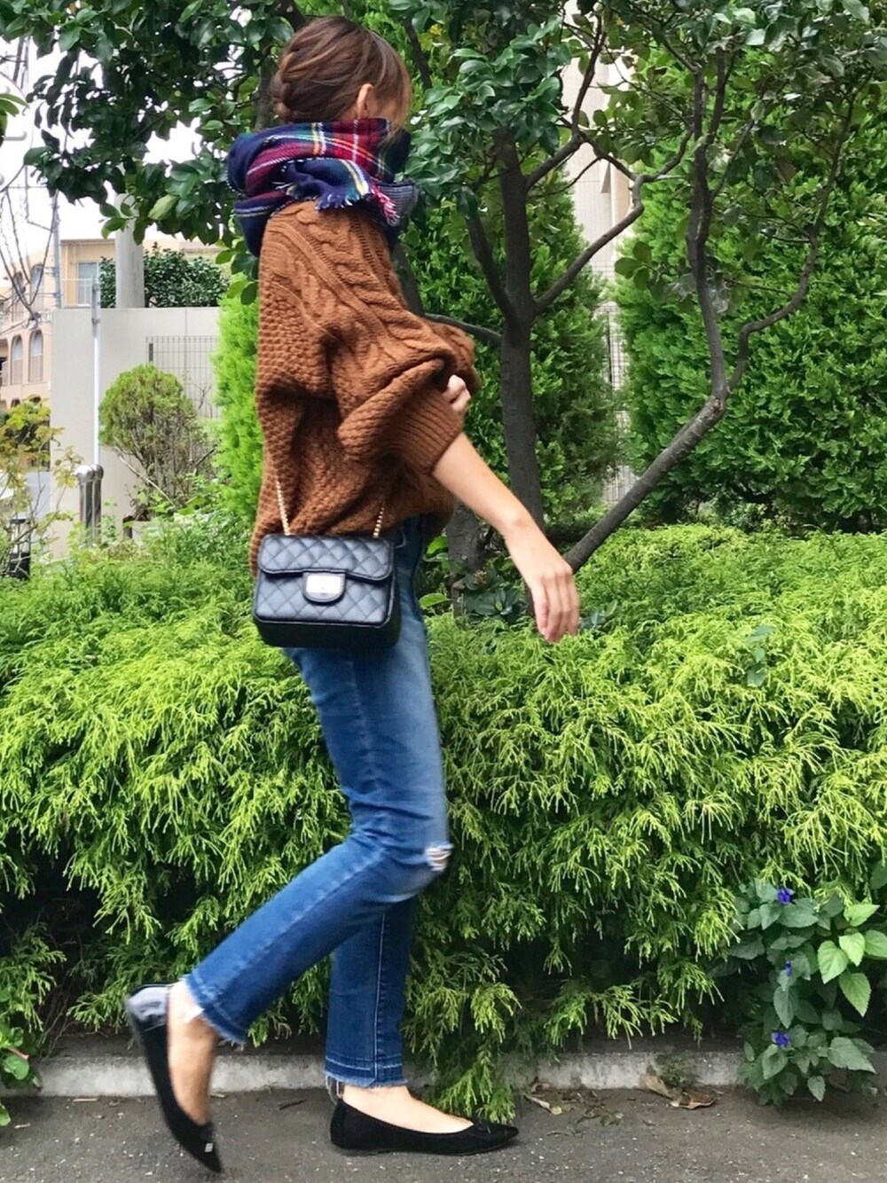 ブラウン系のニット/セーター、ブラック系のショルダーバッグ、ブルー系のデニムパンツを着用したレディースの秋コーディネートの1枚目の写真