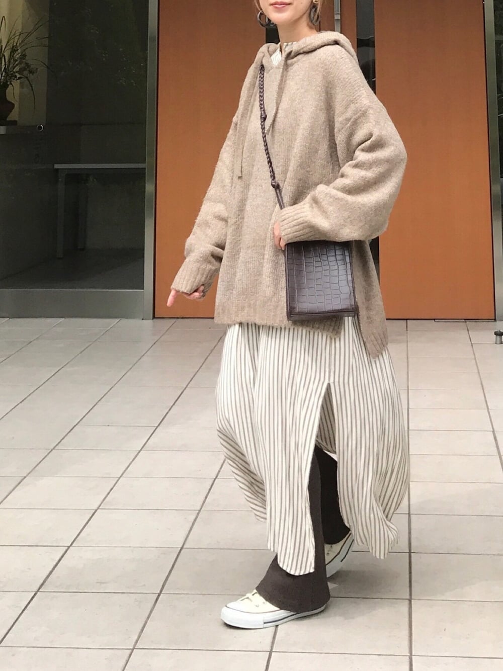 ベージュ系のニット/セーター、ホワイト系のワンピース、ブラウン系のレギンス/スパッツを着用したレディースの秋コーディネートの1枚目の写真