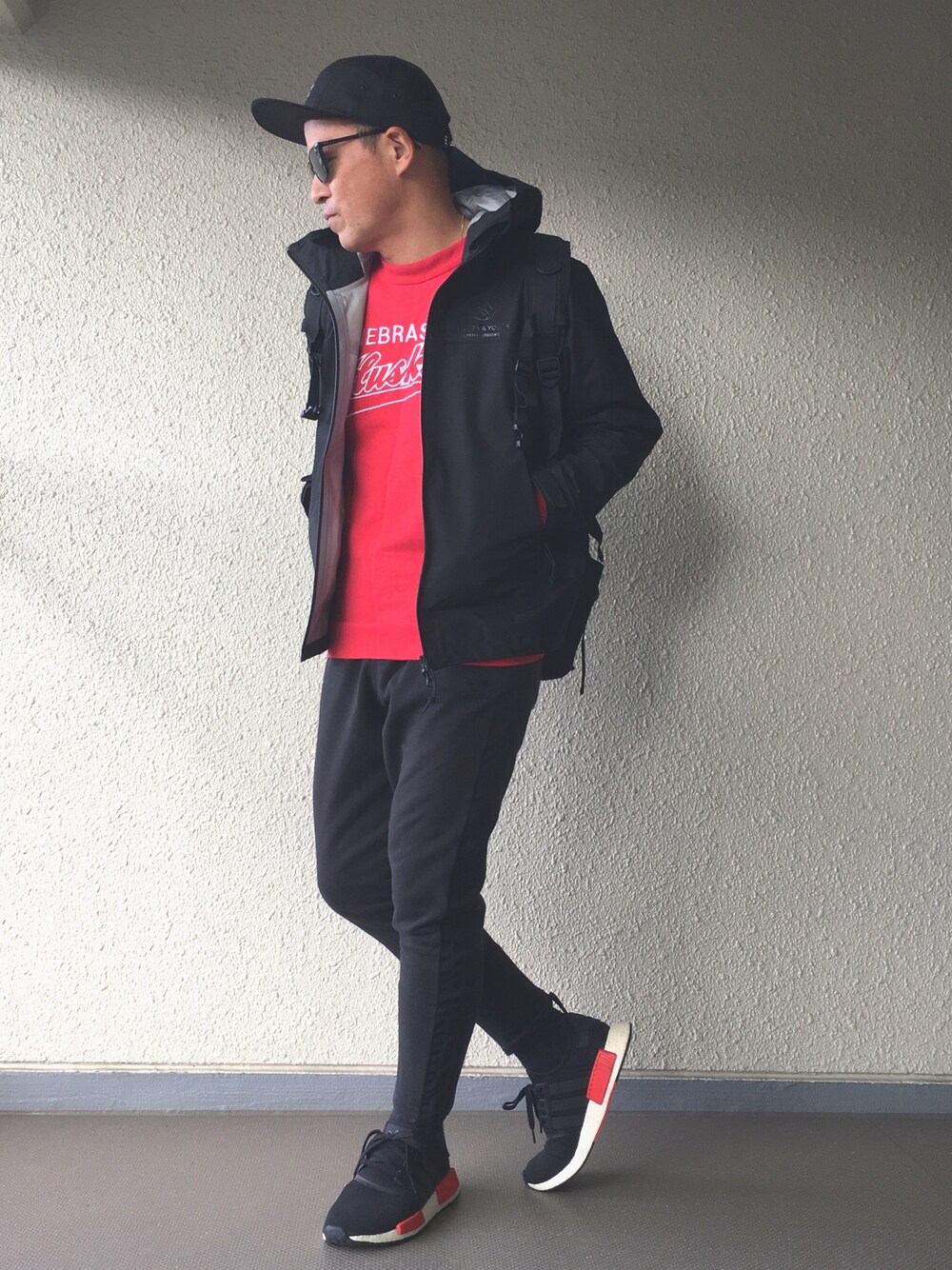 ブラック系のマウンテンパーカー、レッド系のスウェット、ブラック系のパンツを着用したメンズの秋コーディネートの1枚目の写真