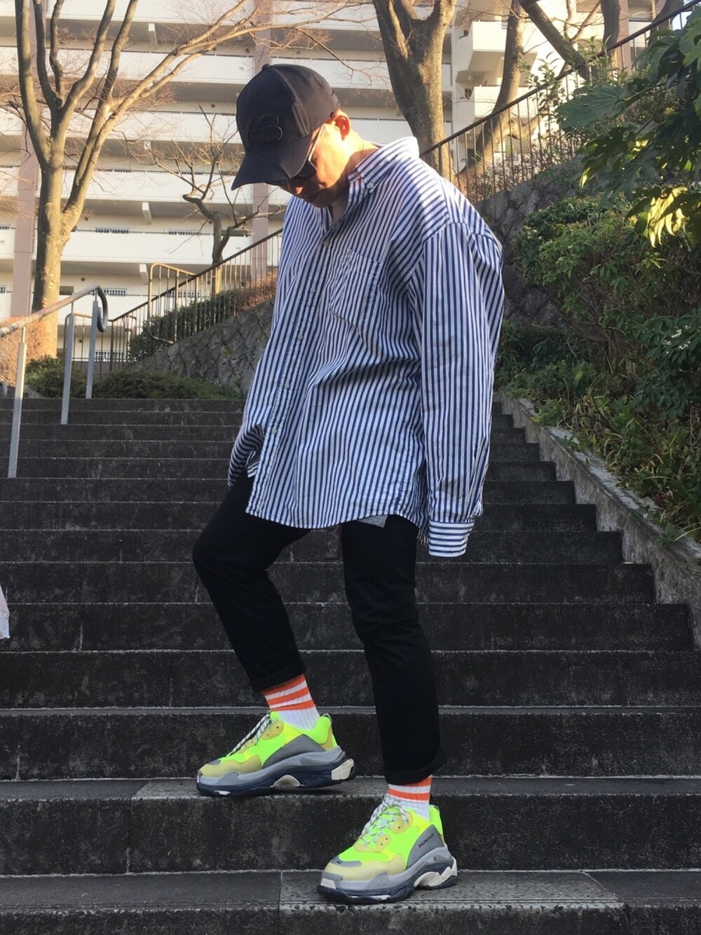 ブルー系のシャツ/ブラウス、イエロー系のスニーカー、ブラック系のパンツを着用したメンズの春コーディネートの1枚目の写真