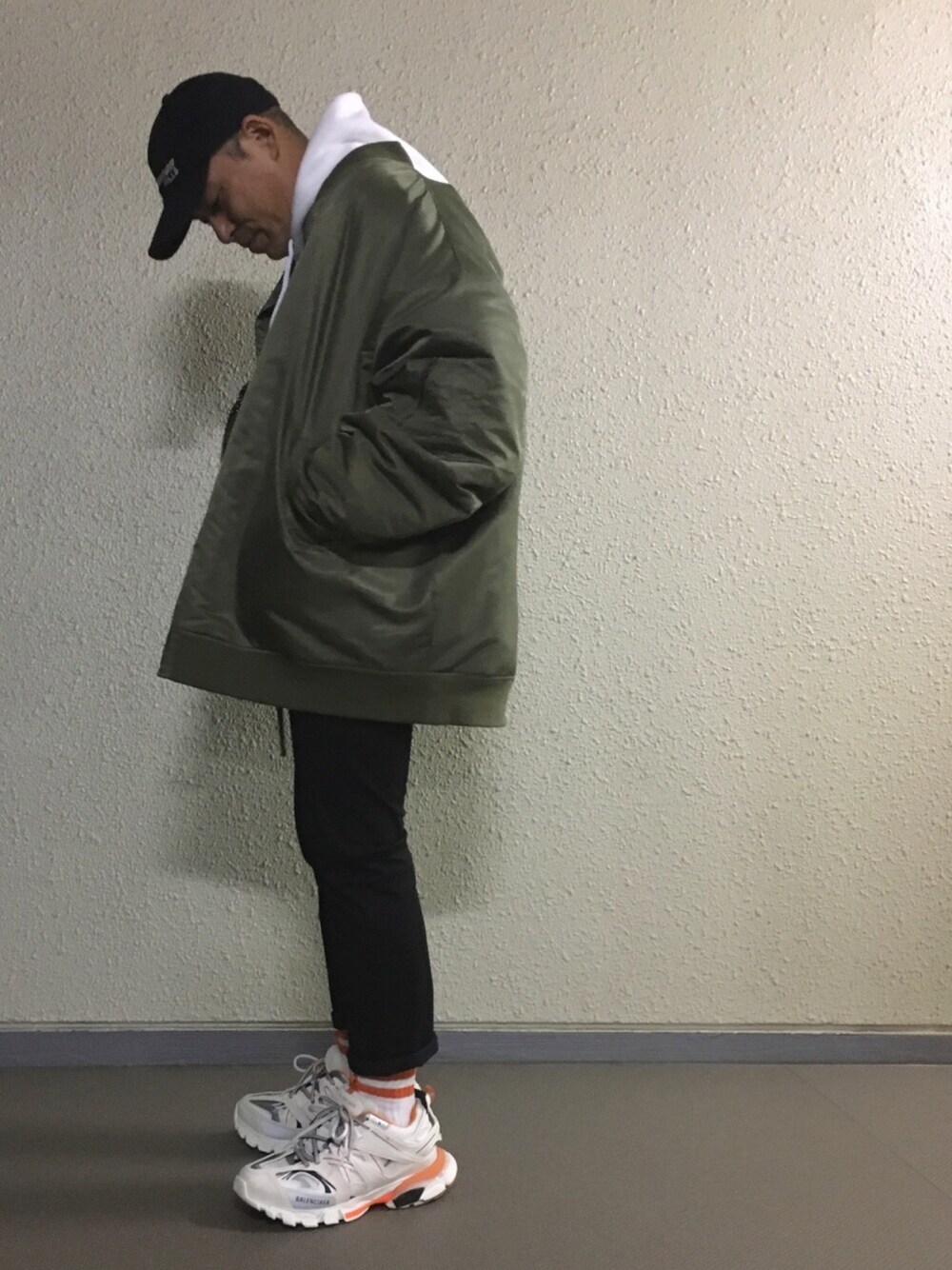 ホワイト系のパーカー、グリーン系のMA-1、ブラック系のパンツを着用したメンズの春コーディネートの1枚目の写真
