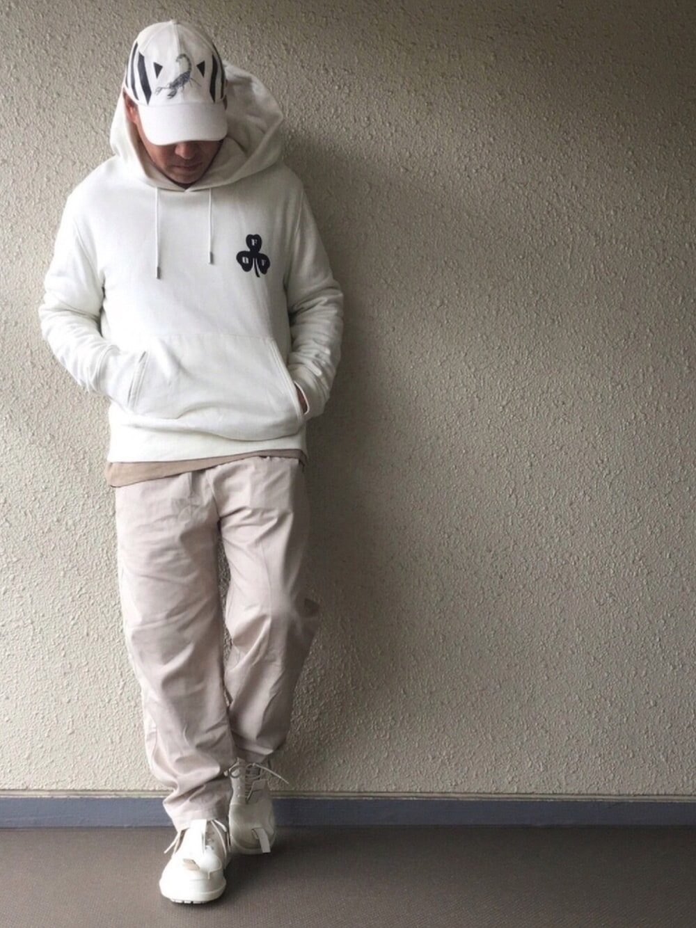 ホワイト系のパーカー、ベージュ系のパンツ、ホワイト系のレインシューズを着用したメンズの春コーディネートの1枚目の写真