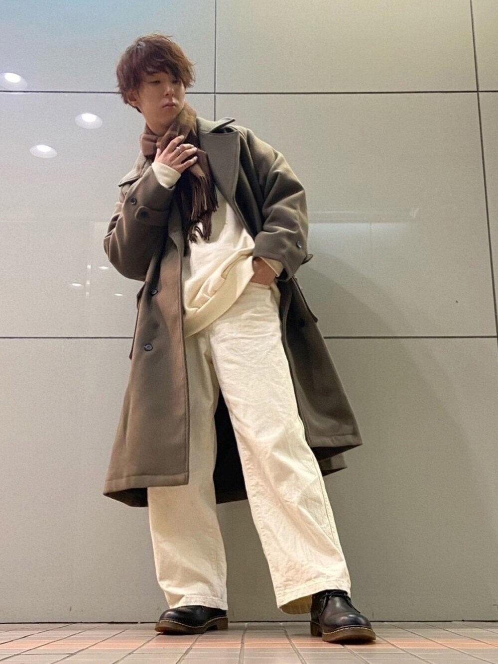 グレー系のチェスターコート、ホワイト系のデニムパンツ、ホワイト系のスウェットを着用したメンズの冬コーディネートの1枚目の写真
