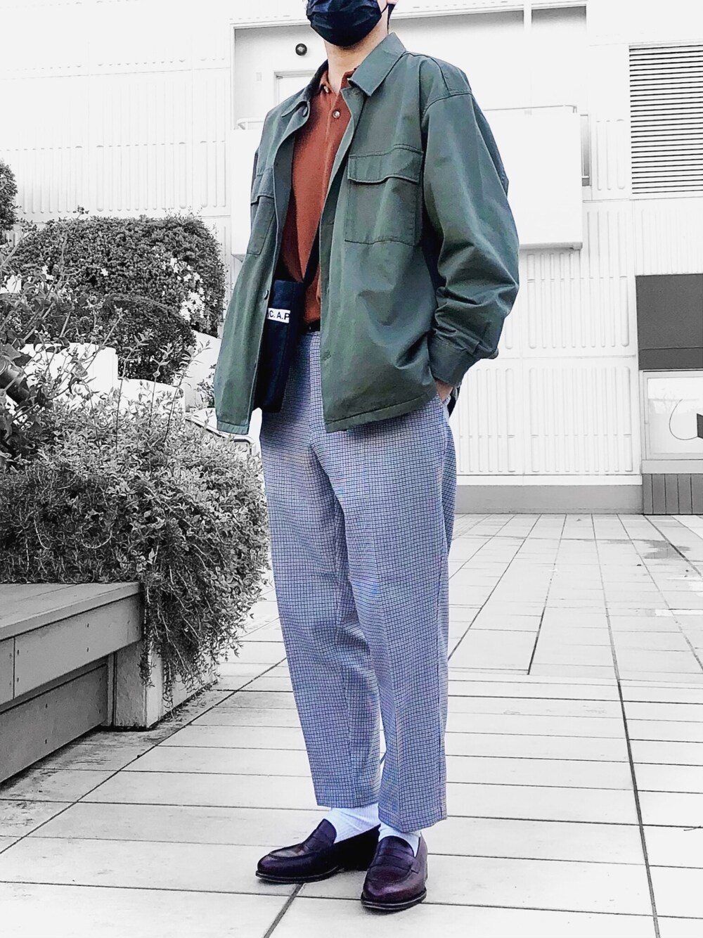 グリーン系のシャツ/ブラウス、オレンジ系のニット/セーター、ブラック系のボディバッグ/ウエストポーチを着用したメンズの春コーディネートの1枚目の写真