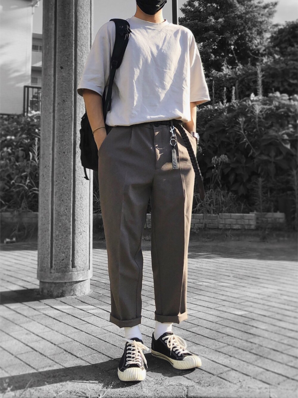 グレー系のTシャツ/カットソー、ブラック系のバックパック/リュック、ブラウン系のスラックスを着用したメンズの秋コーディネートの1枚目の写真