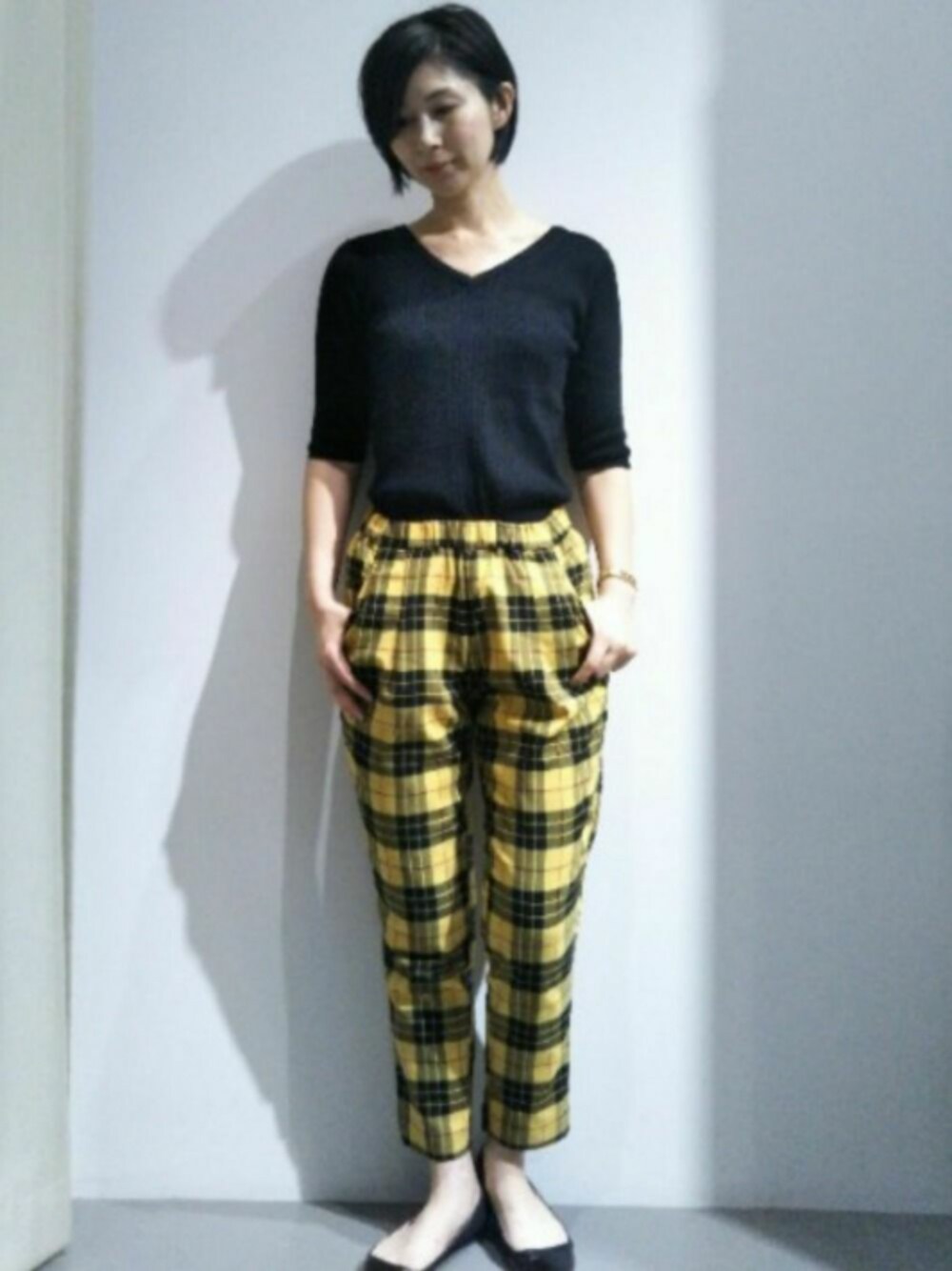 ブラック系のトップス、イエロー系のその他パンツを着用したレディースの夏コーディネートの1枚目の写真