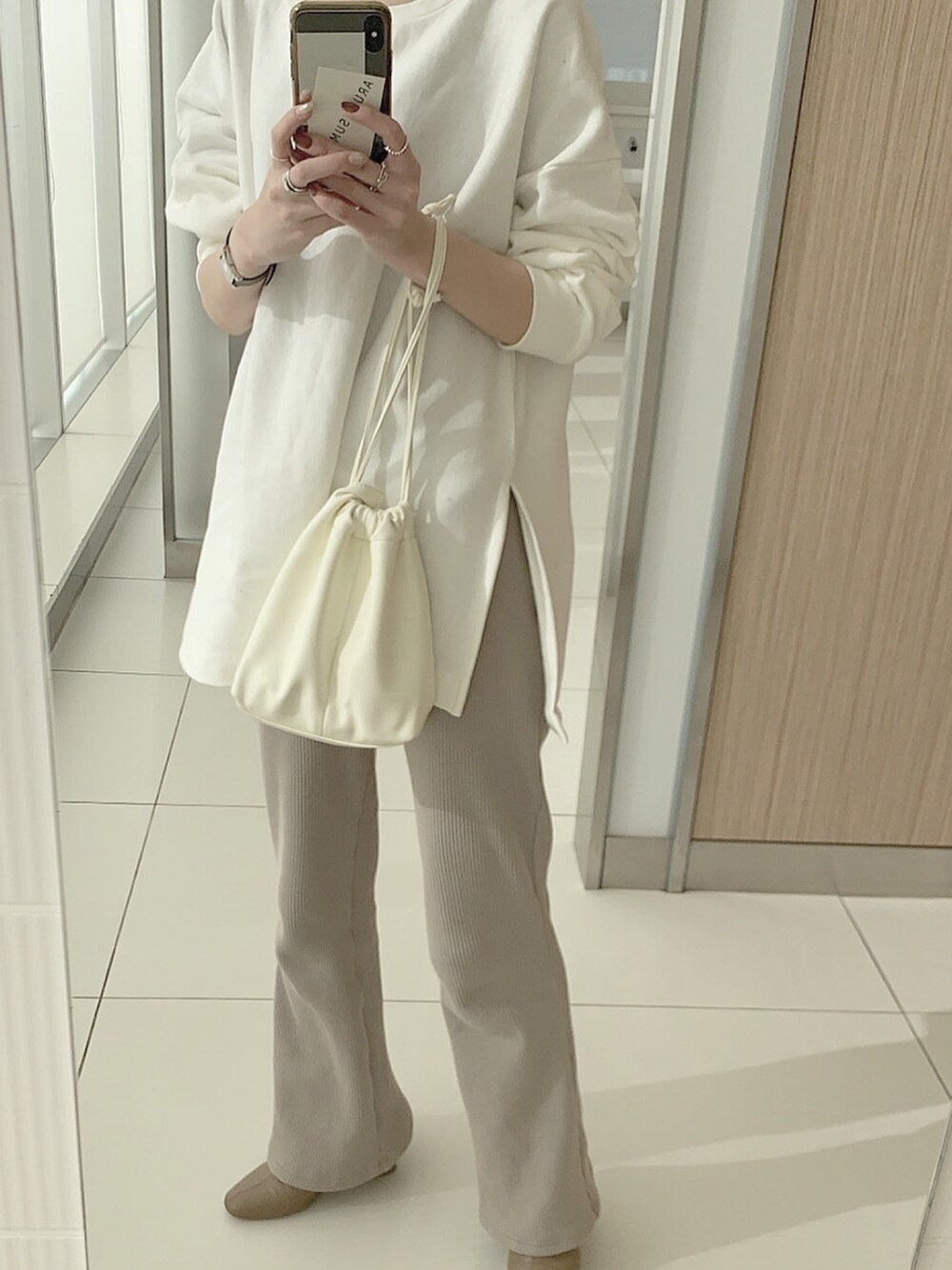 ホワイト系のハンドバッグを着用したレディースの冬コーディネートの1枚目の写真