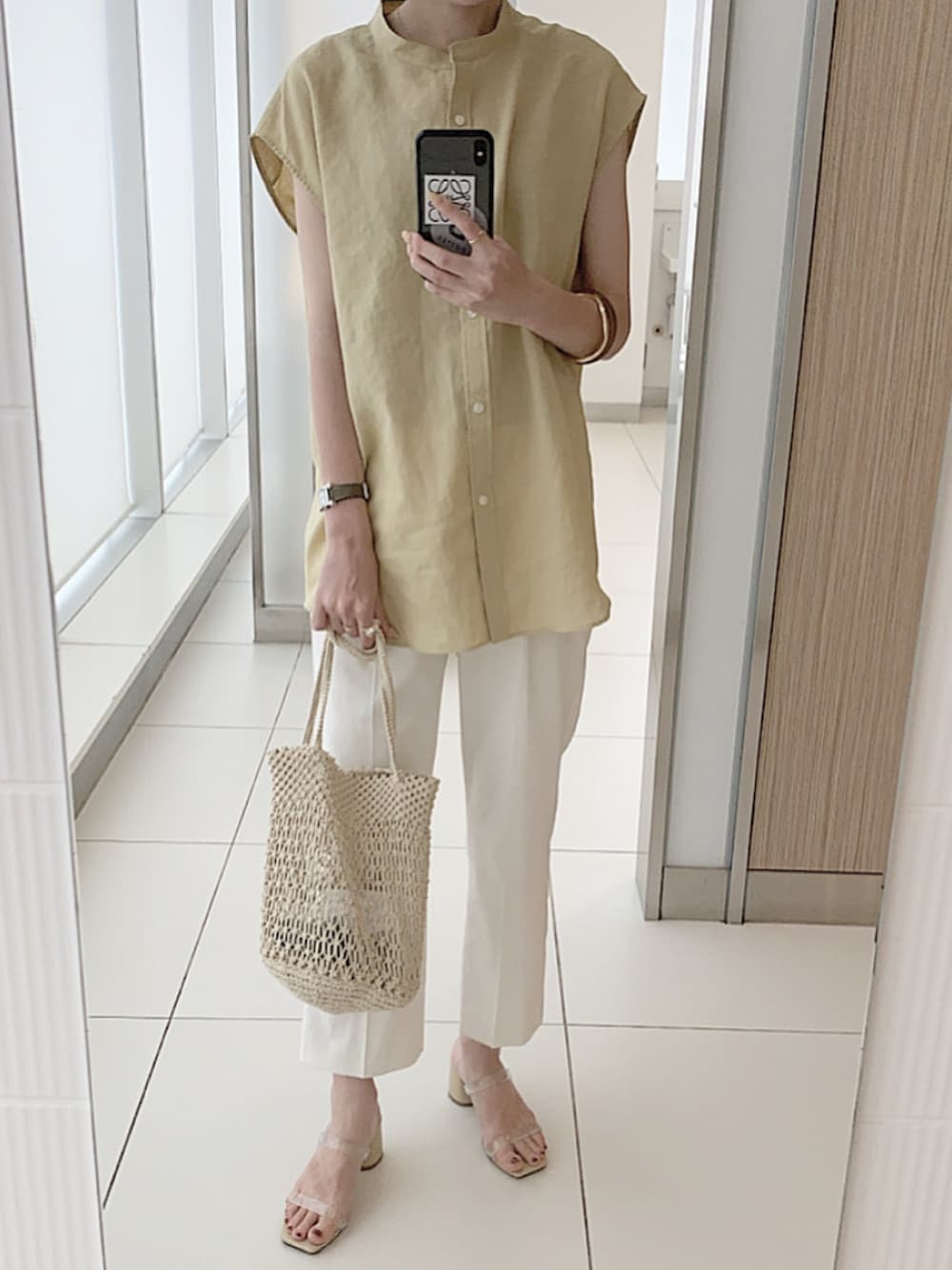 イエロー系のシャツ/ブラウス、ホワイト系のパンツ、ベージュ系のサンダルを着用したレディースの夏コーディネートの1枚目の写真