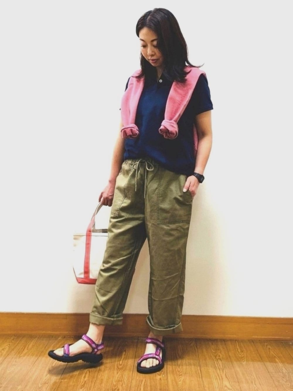 ブルー系のポロシャツ、ピンク系のパーカー、グリーン系のパンツを着用したレディースの春コーディネートの1枚目の写真